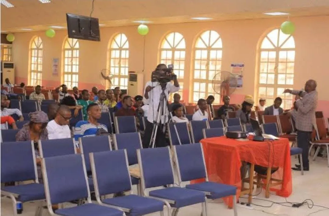 A seminar hall with rows of chairs and a camera crew